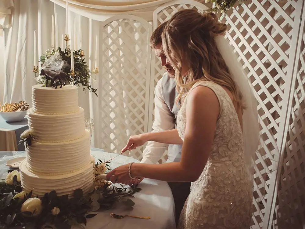 couple cutting wedding cake in banquet room Credit: Rick & Stephanie Osborne, Ardent Photography